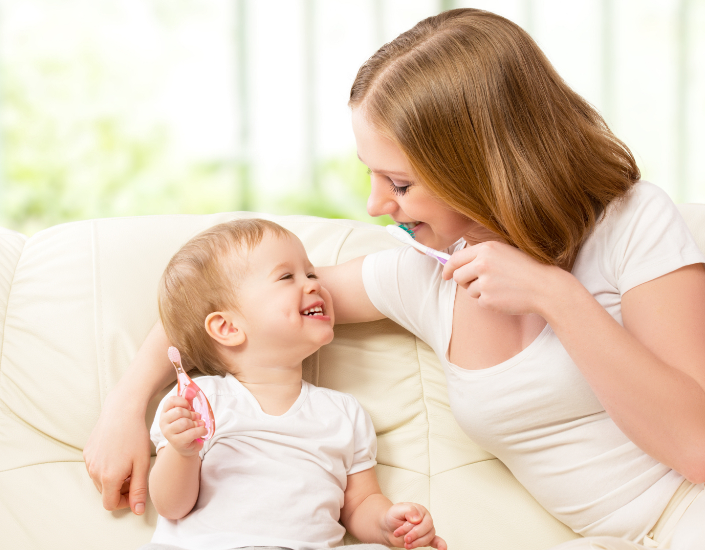Glückliche Mutter singt mit ihrem lachenden Kind lustige Zahnputzlieder
